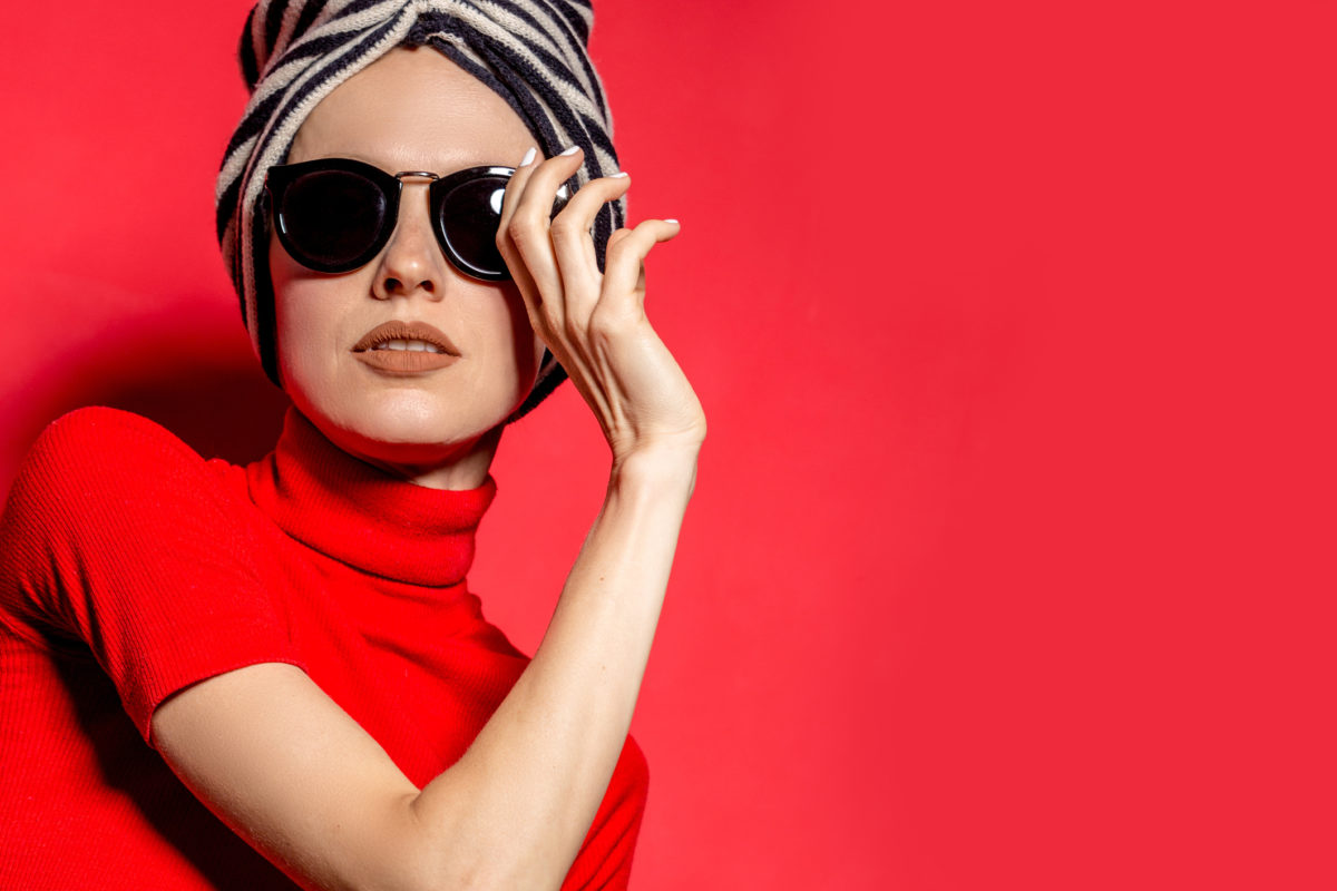 Beautiful elegant portrait of young woman in fashion autumn clothes, studio shot over red