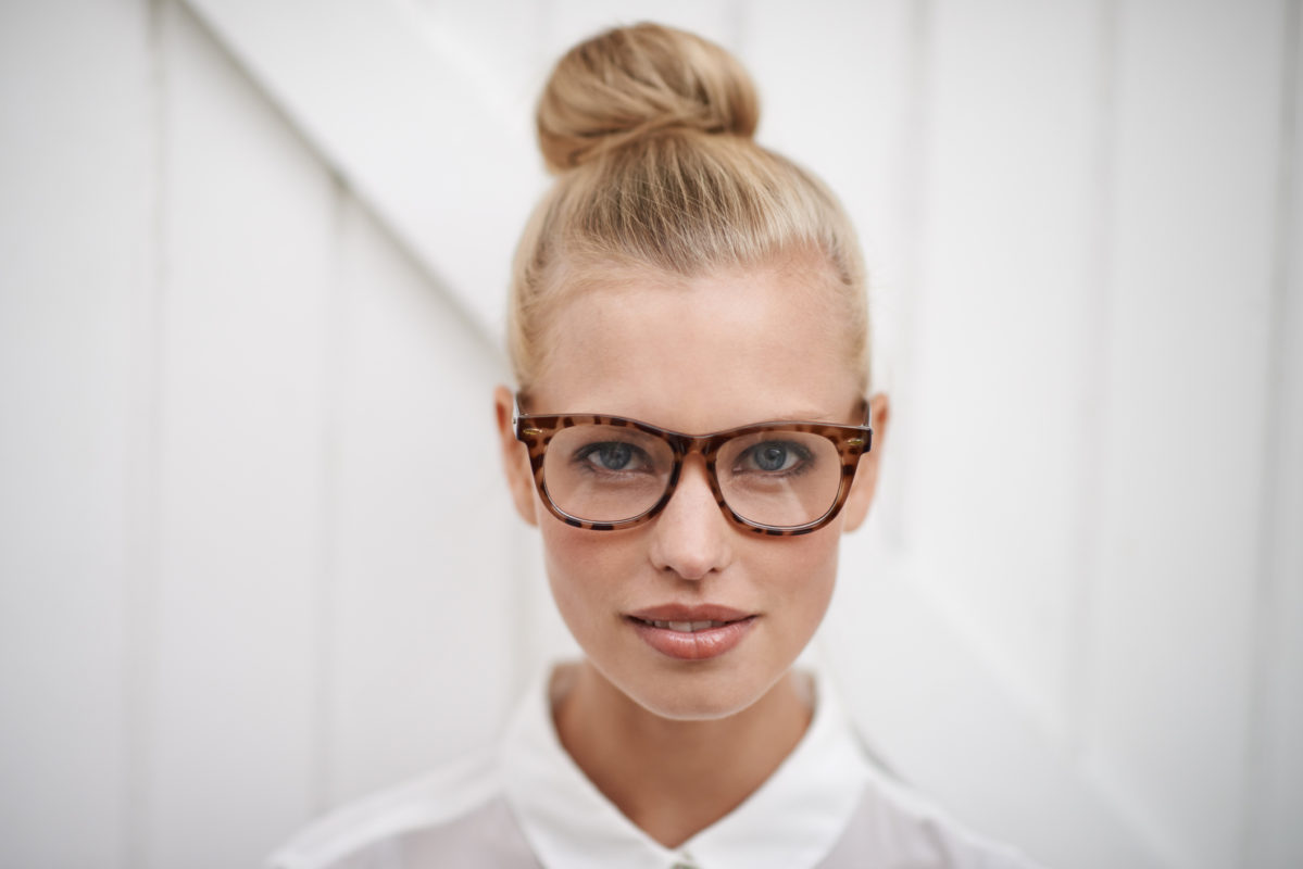 A young woman wearing a blouse and spectacles