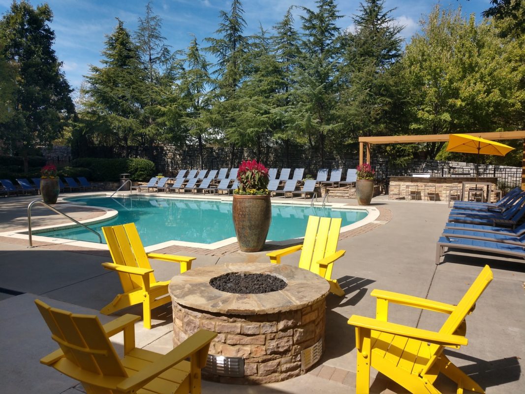 Yellow chairs around a poolside fire pit