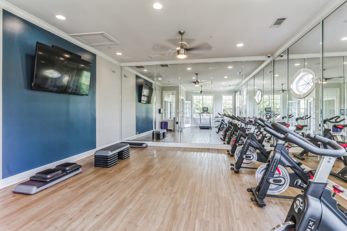 Fitness center with large TV, treadmills, cycles and a large mirror wall