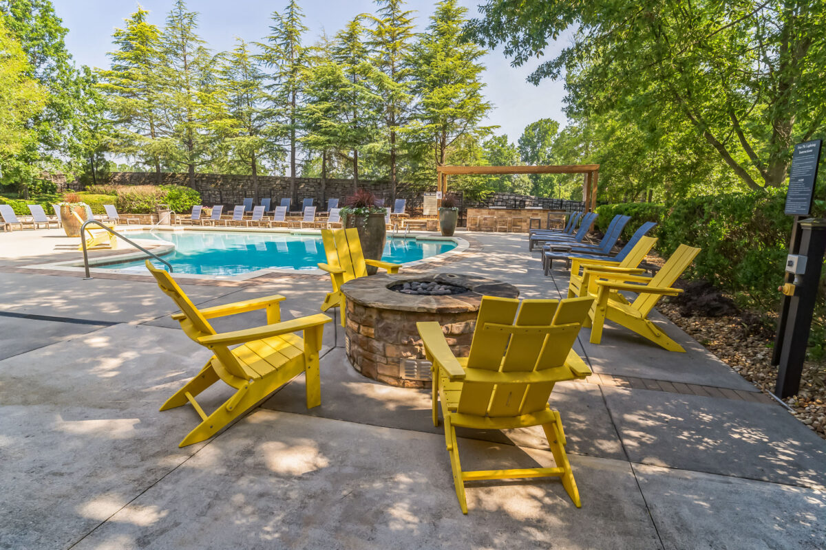 Yellow chairs around a poolside fire pit
