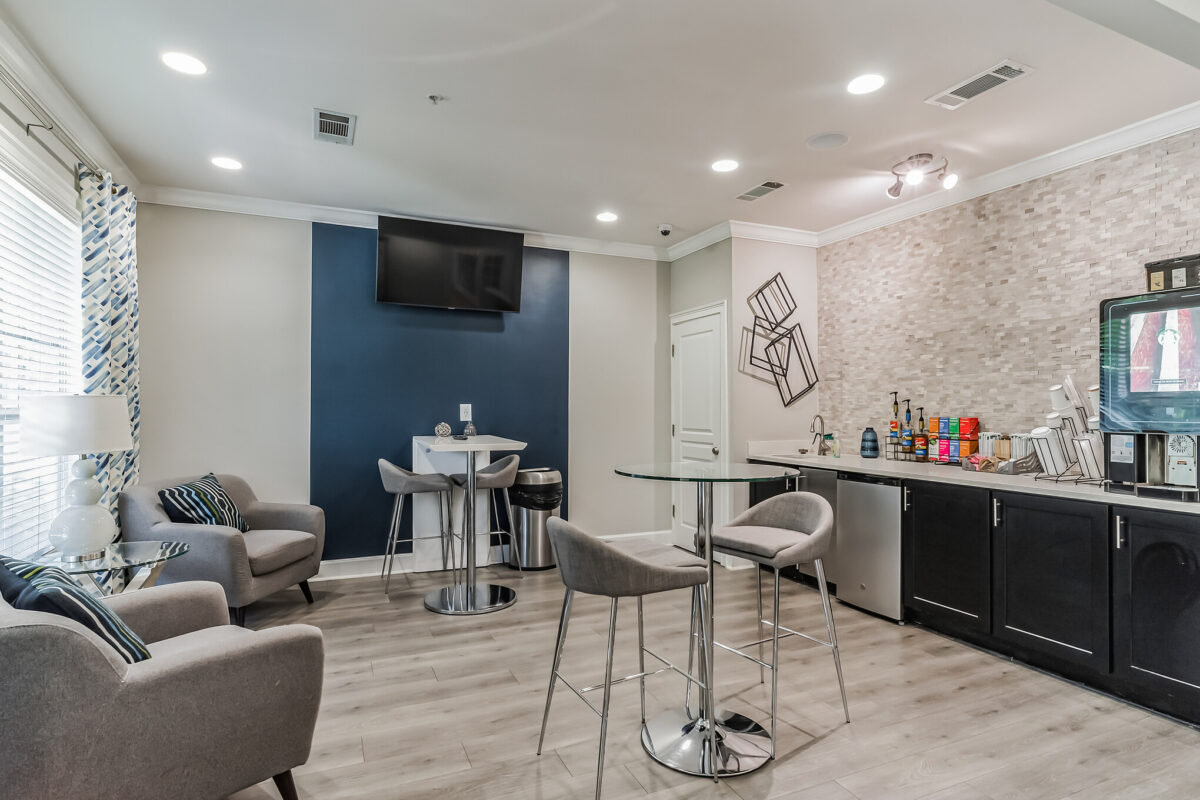Common space and kitchen with chairs and tables and wall-mounted television set.