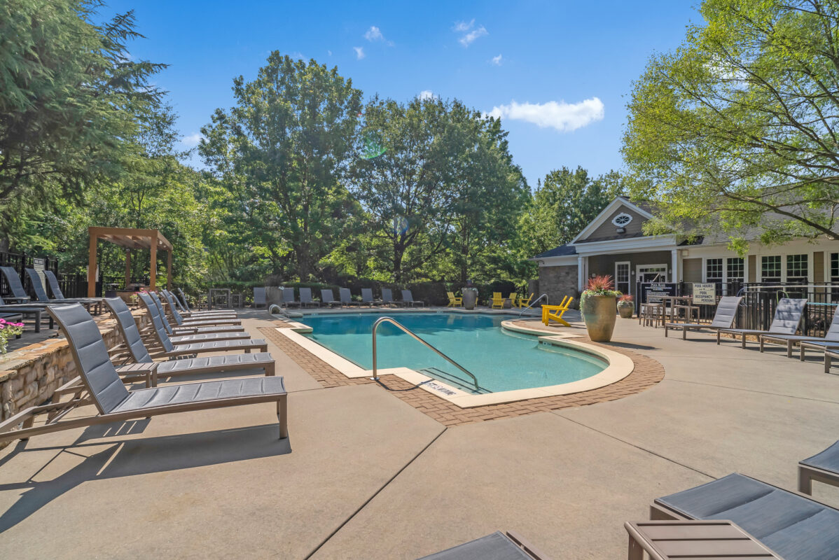 pool with lounge seating with clubhouse in the background